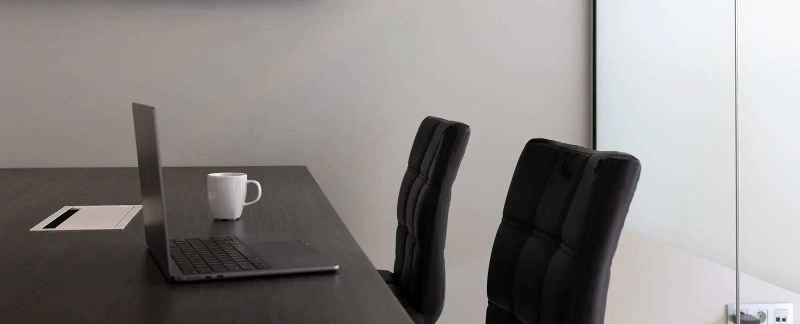 Sala de reuniones con mesa, sillas, portátil y televisor en la pared